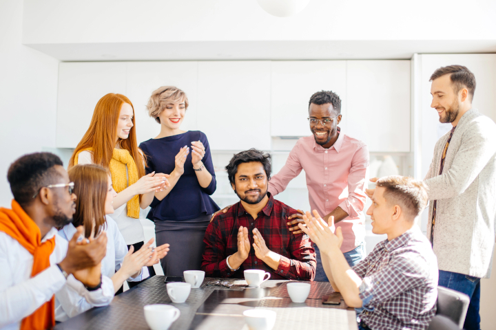 Building a Workplace Appreciation Tradition During the Holidays – workers applauding and congratulating a worker Building a Workplace Appreciation Tradition During the Holidays - workers applauding and congratulating a worker